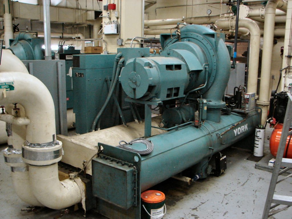 Large YORK industrial chiller unit with connected pipes inside a mechanical equipment room
